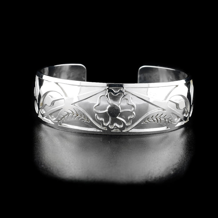 The center of this hummingbird bracelet has a flower with two leaves. On both sides of the flower are the heads of two hummingbirds facing inward and drinking from the flower.