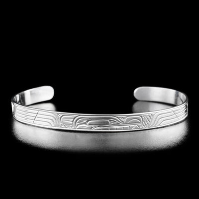 Sterling Silver 1/4" Wolf Bracelet by Victoria Harper. In the center of the bracelet is the profile of a wolf's head facing towards the right with a long snout and teeth showing. The designs on both side of the wolf's head are identical; the artist has hand-carved abstract lines to represent the fur on the wolf's body. The "background" on this bracelet is a crisscross pattern that the artist has hand-carved to allow for the wolf legend to stand out.