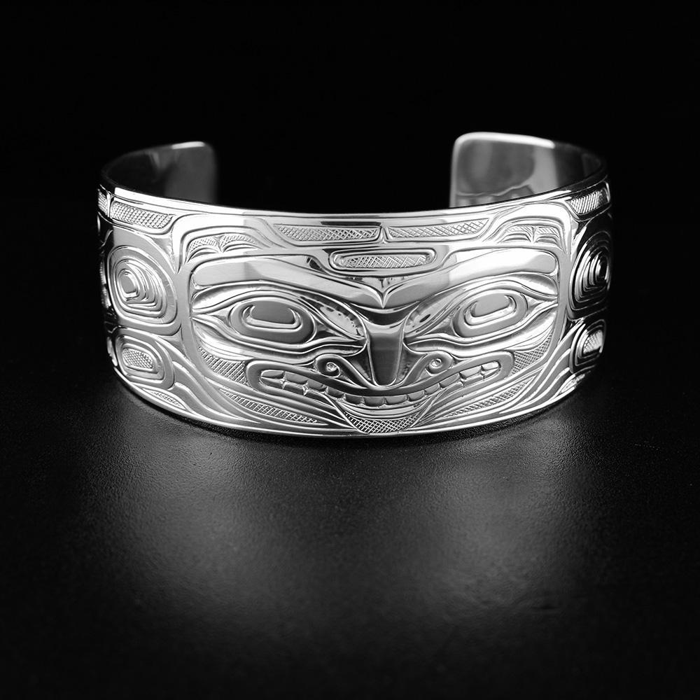 This sterling silver cuff bracelet has a wide band with a gap in the back. There are carvings on the surface of the band depicting the Bear.