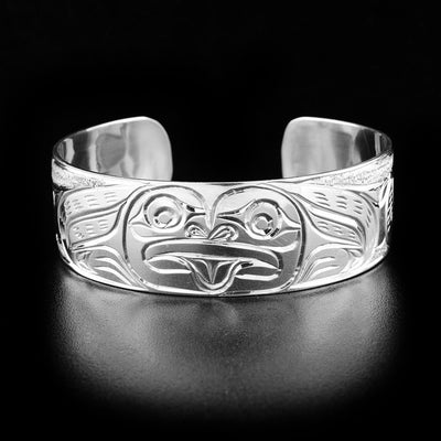 Sterling Silver 3/4" Frog Bracelet by Paddy Seaweed. The design depicts the face of a frog with it's tongue sticking out in the middle of the bracelet. The sides of the bracelet are both the continuation of its body with hand carved legs. The background has been delicately carved to allow for the image of the frog to pop out.