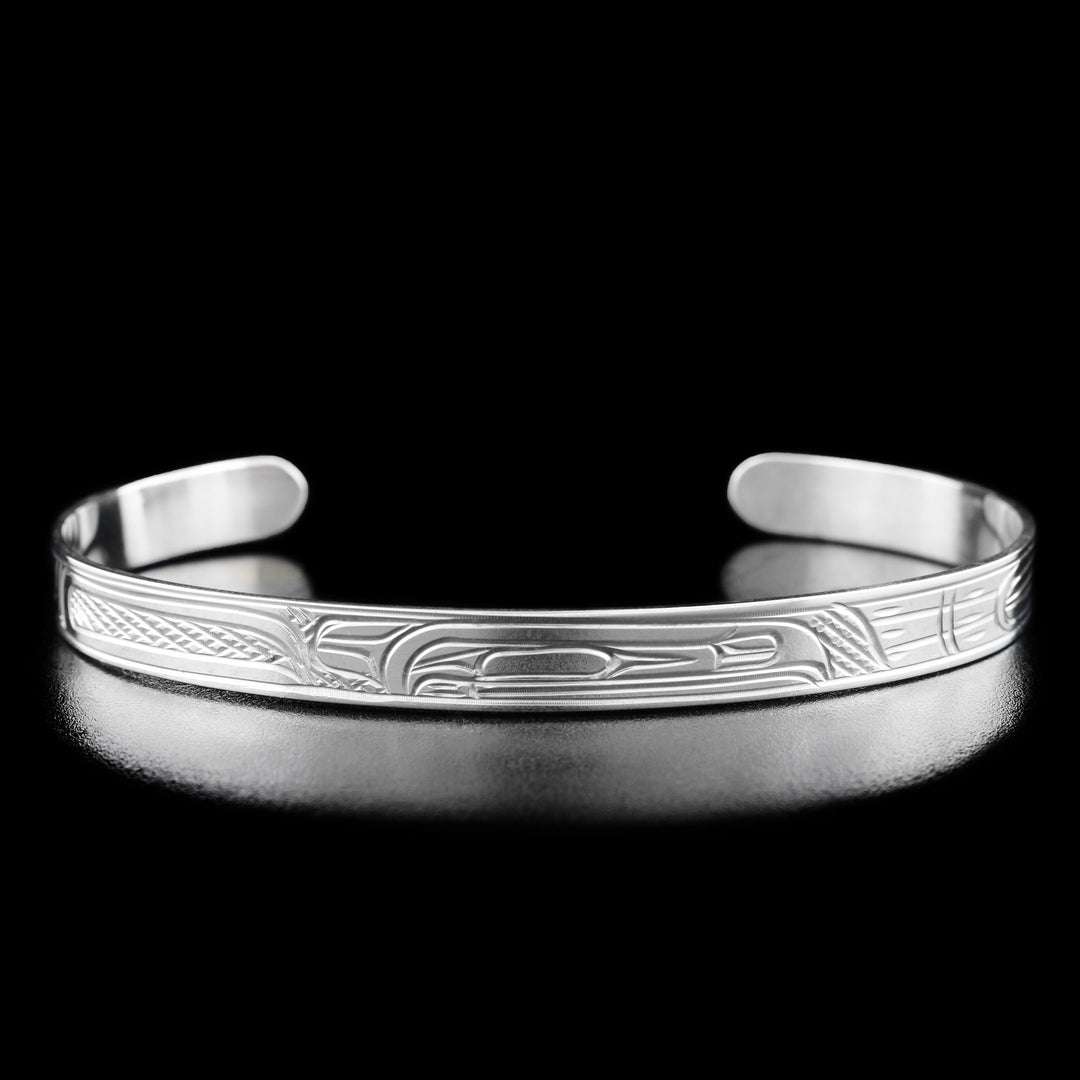 This Raven bracelet is made from sterling silver and has a thin band with a gap in the back. There is a depiction of the Raven that has been carved into the surface of the band.