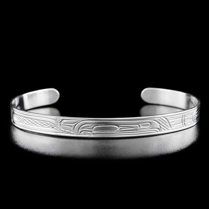 This Raven bracelet is made from sterling silver and has a thin band with a gap in the back. There is a depiction of the Raven that has been carved into the surface of the band.