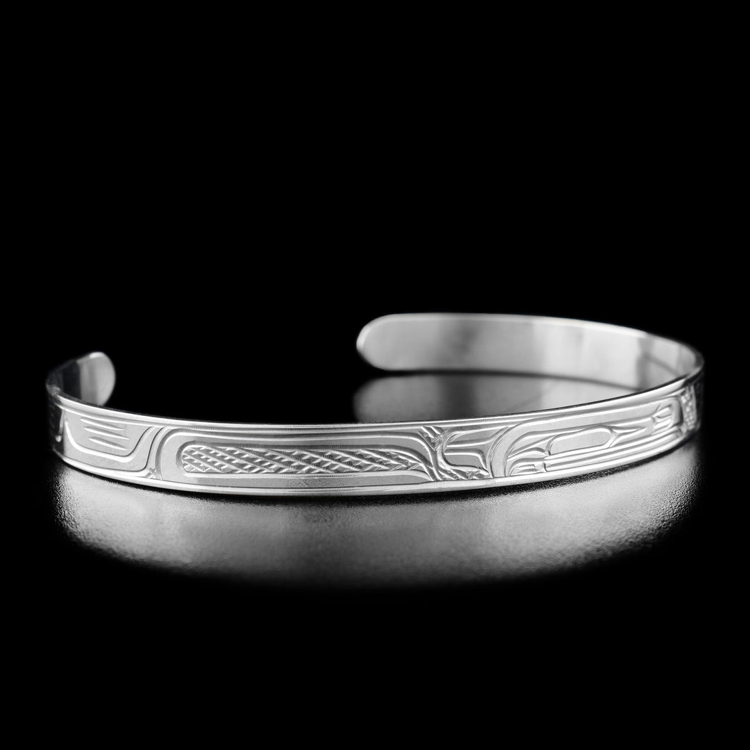 This Raven bracelet is made from sterling silver and has a thin band with a gap in the back. There is a depiction of the Raven that has been carved into the surface of the band.