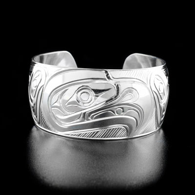 Sterling Silver 1" Eagle Bracelet by Paddy Seaweed. The design depicts the profile of an eagle's head looking to the right in the center of the bracelet. Along the sides are delicately hand carved feathers to represent the eagle's wings. The background has been neatly hand carved to allow for the image of the eagle to stand out.