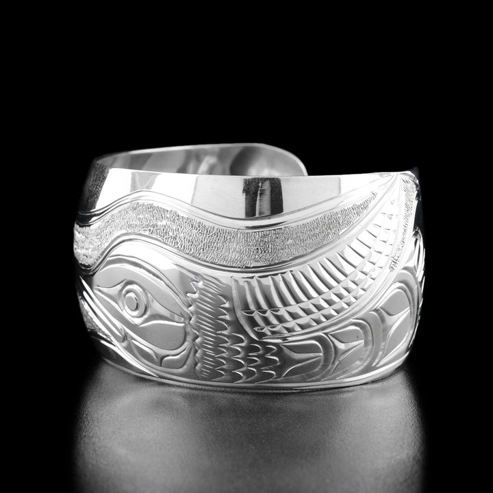 Right angle photo of the bracelet shows the hummingbird's body and outstretched wing with carved designs representing the feathers.