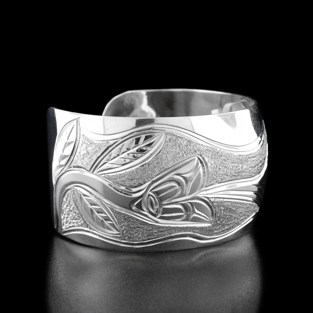 Left angle photo of the bracelet shows a flower with a long stem and leaves that the hummingbird is drinking out of.