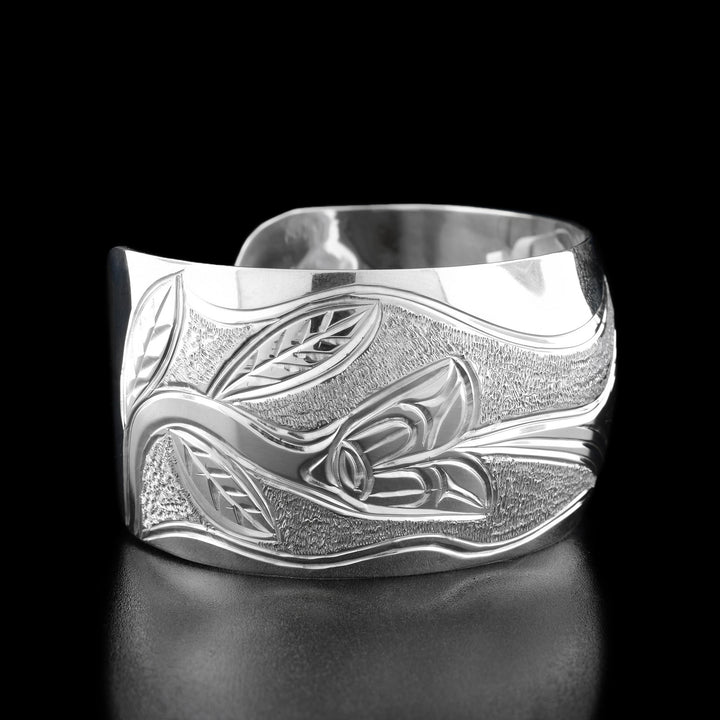 Left angle photo of the bracelet shows a flower with a long stem and leaves that the hummingbird is drinking out of.