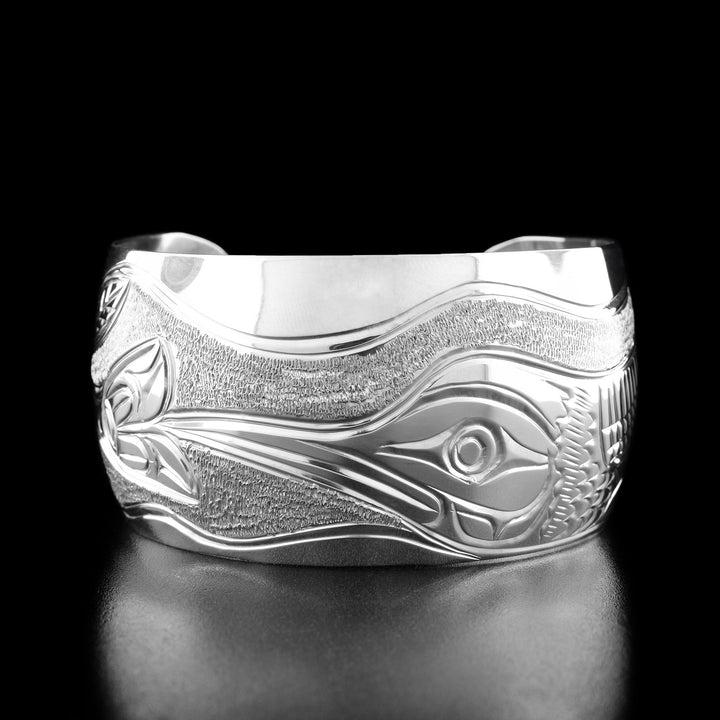 The center of this hummingbird bracelet has the profile of a hummingbird's head with a long, narrow beak facing the left and drinking out of a flower.