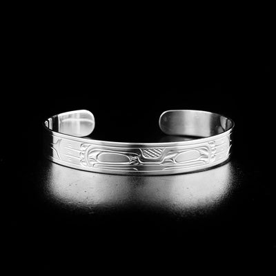 Sterling Silver 3/8" Frog Bracelet by Victoria Harper. In the center of the bracelet the artist has hand-carved the face of a frog looking forward. On both sides of the bracelet there are intricate designs representing the body, arms, and legs of the frog.
