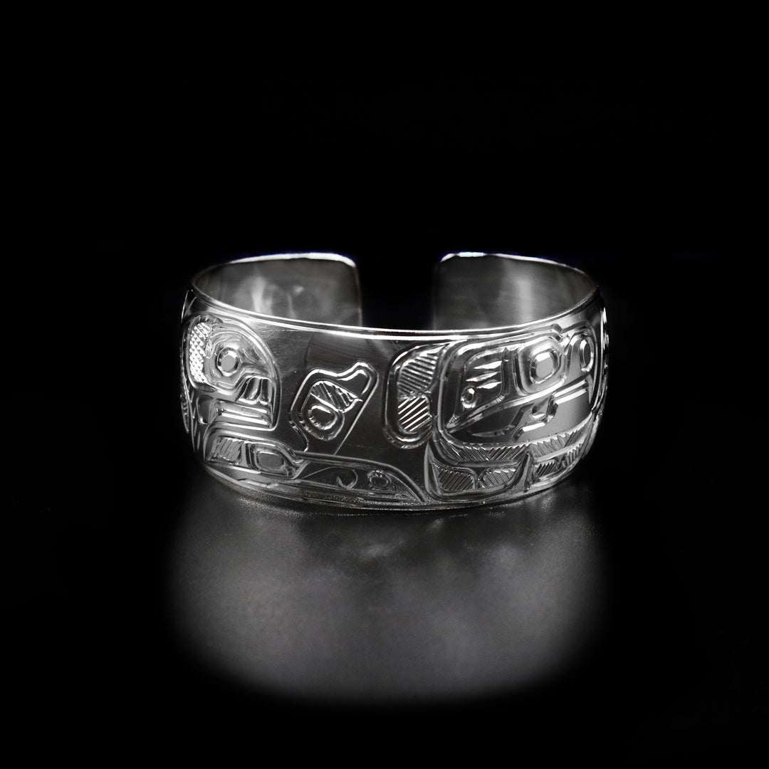 This 1" Eagle and Orca Bracelet is hand carved by Heiltsuk artist Ivan Wilson. He has used sterling silver to create this piece. The bracelet measures 6.5" in length, 1.0" in width, and has a 0.5" gap. The Eagle Legend Represents: POWER, INTELLIGENCE, VISION. The Orca Legend Represents: LONGEVITY, PROTECTION, FAMILY.
