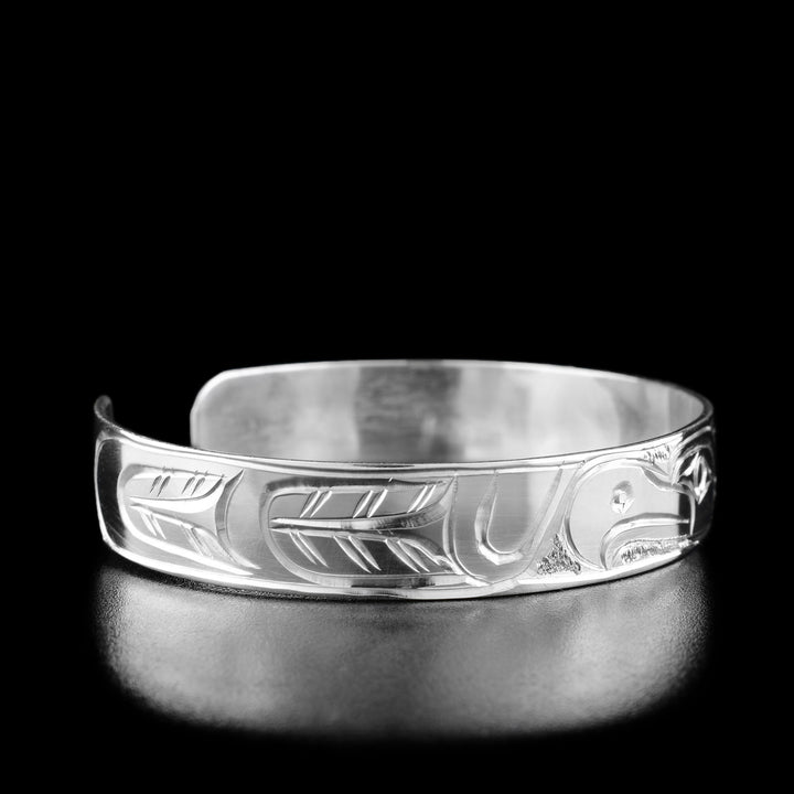 Left angle photo of the bracelet shows carved designs representing the thunderbird's wing with feathers.