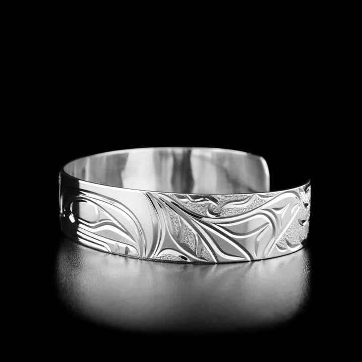 Right angle photo of the bracelet shows carved designs representing the fin of the orca and the waves around it.