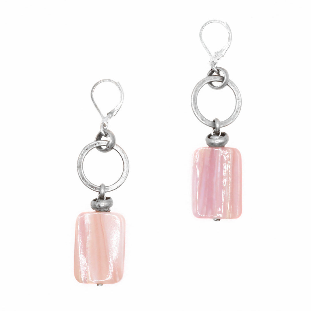 These pink mother of pearl earrings have large rectangle shaped hangs made from the mother of pearl. There is a large sterling silver hoop hanging from the hooks and the hangs dangle from the hoops.