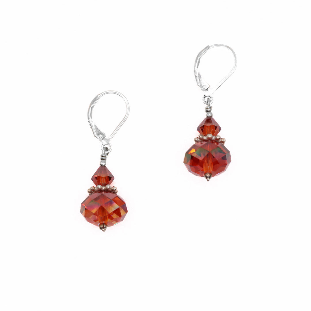 These red crystal earrings are made from sterling silver and beautifully cut red Swarovski crystals. The gems are stacked and have a silver charm in between them on these drop earrings.