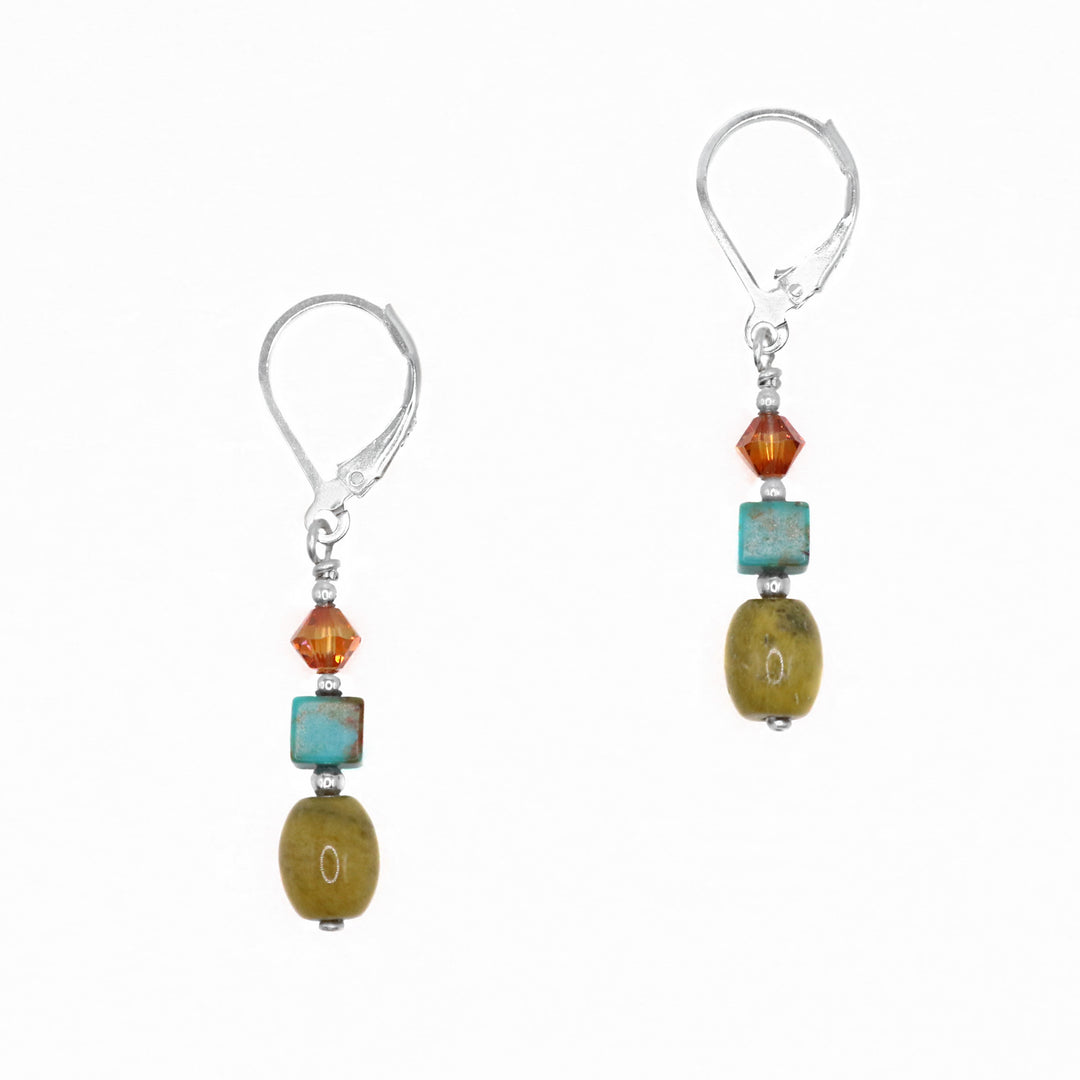 These unique turquoise drop earrings are made from sterling silver, Swarovski crystal, blue turquoise and yellow turquoise gems. There is a small, diamond shaped and burgundy crystal, square turquoise charm and oval shaped yellow turquoise. The hangs are dangling from the hooks.
