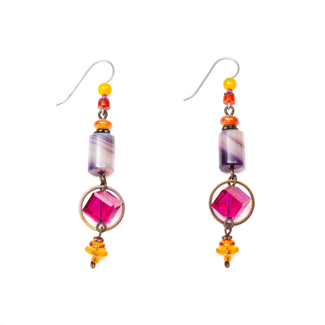 These unique crystal drop earrings have been made using amber, glass, carnelian agate, Austrian crystal, dyed agate, and mother of pearl. There are amber and agate clusters at the top and bottom of the piece. Below the cluster is cylinder shaped mother of pearl and square, pink crystals with brass hoops around them. 