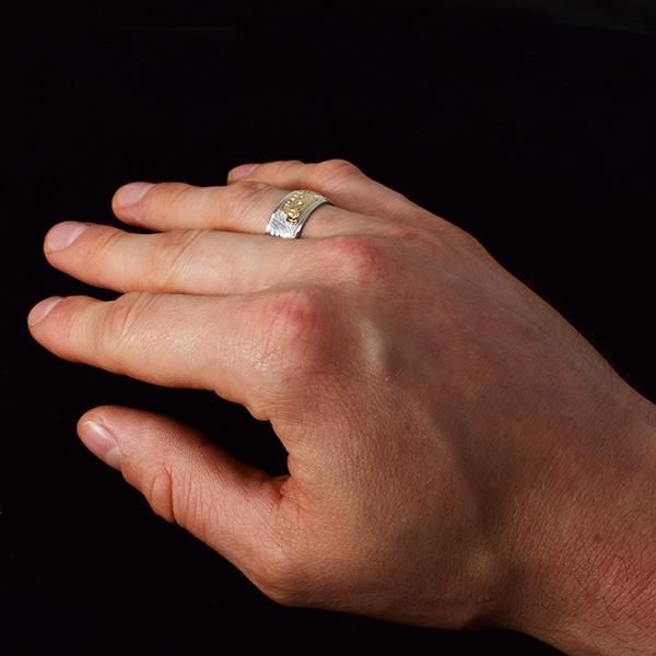 This silver Wolf ring is made from sterling silver and 14K gold and has a single band. There is a depiction of the Wolf carved into the surface of the band and the head of the Wolf is made from 14K gold.