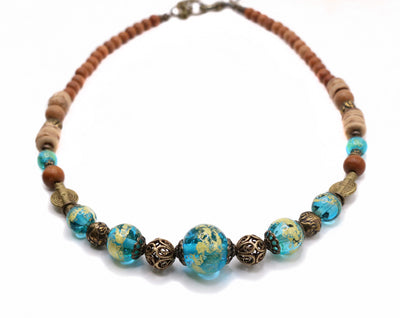 This Urban Tribe Necklace is handcrafted by artist Wendy Pierson (Island Rain Studio). It featues her lampworked glass, bronze adornments throughout the necklace, and sandalwood near the chain. The necklace measures up to 21" long.
