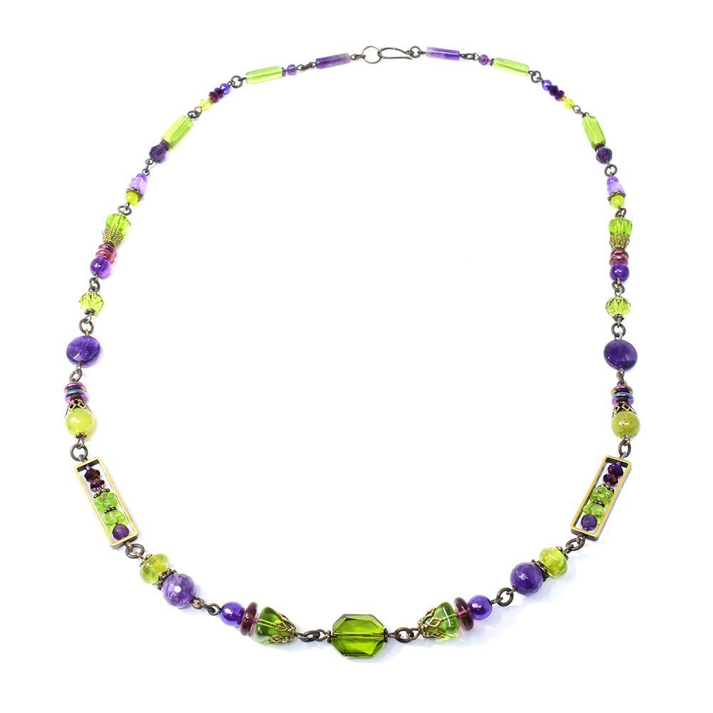 This beaded, multiple gemstone necklace is made from serpentine jade, Austrian crystal, amethyst, peridot and pressed glass. There are beads of various shapes and material that are held together by hand worked, brass links.