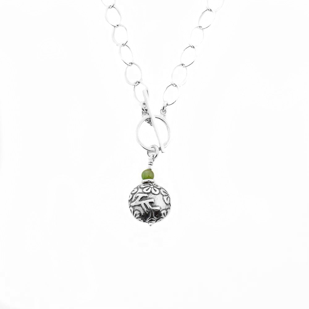 This jade pendant has been made using sterling silver, antique silver, and BC jade to create this piece.  The pendant, including the toggle clasp, measures 1.38" x 0.50". The chain is 20" long.