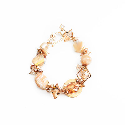 This Champagne Cream Crystal Bracelet is hand crafted by artist Honica. She has used Swarovski crystal, freshwater pearls, handworked brass, gold-filled wire, crystal pearls, mother of pearl, cubic zirconia, glass, and agate to create this piece.  The bracelet is 8.0" long and 0.75" at its widest.