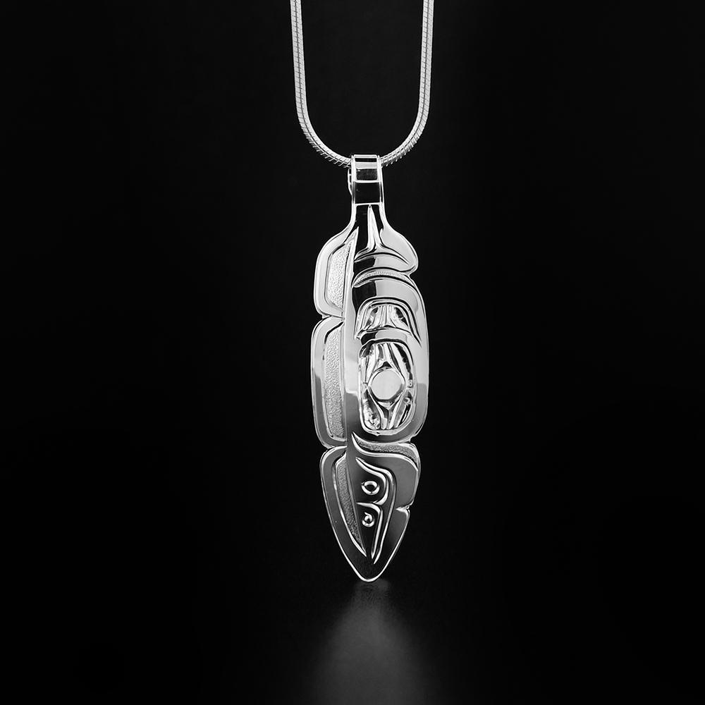 This feather pendant is made from sterling silver and is shaped like a feather. There are carvings on the surface of the pendant that depict the Eagle.