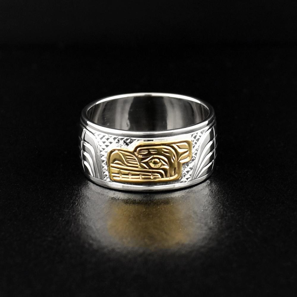 This gold and silver ring is made from sterling silver and 14K gold and has a single, wide band. There is a depiction of the Bear carved into the surface of the band and the head of the Bear is made from 14K gold.