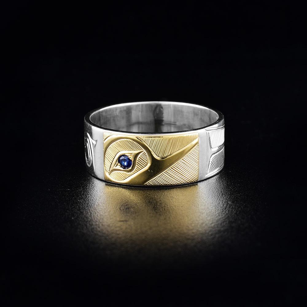 This Hummingbird ring is made from sterling silver, 14K gold and sapphire gemstones. The band is silver with a gold section at the top and there is a depiction of the Hummingbird carved into the gold section of the band. There is a sapphire set into the eye of the legend.