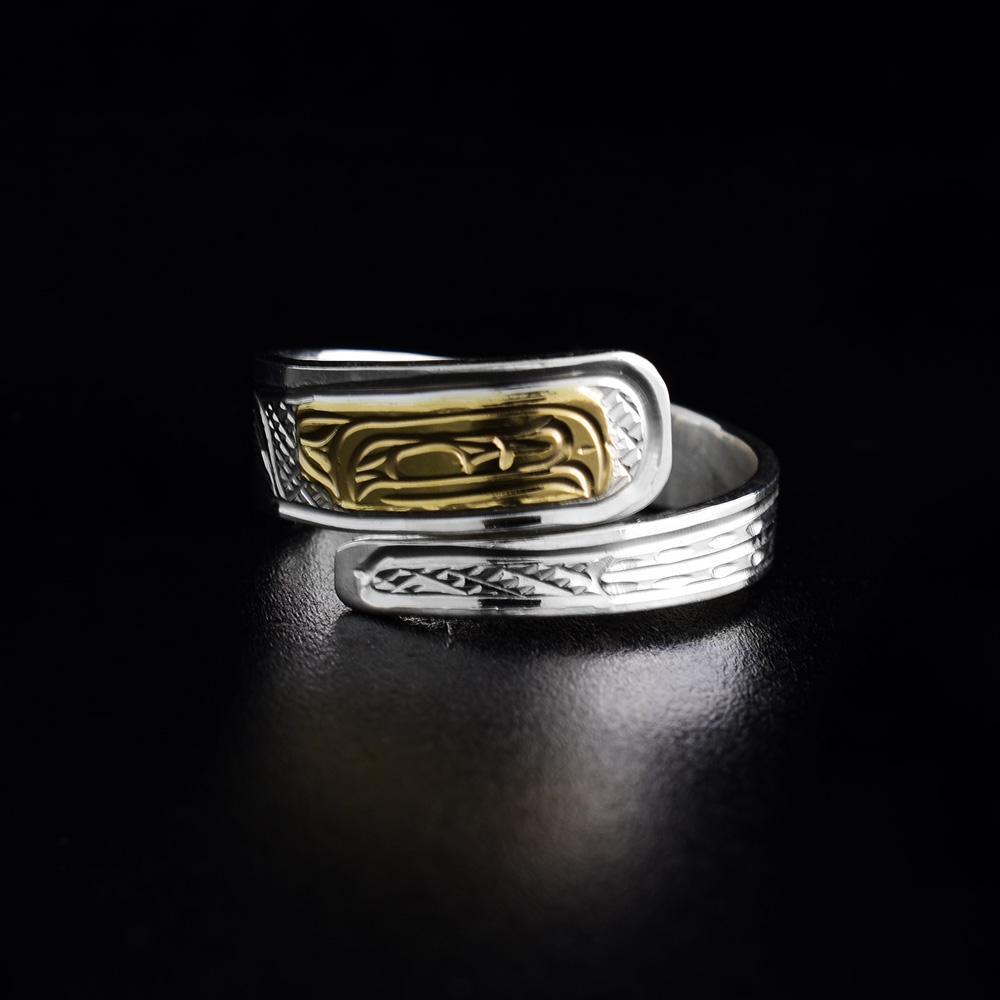 This sterling silver wrap ring has a thin, tapered band that wraps around the finger twice. There is a depiction of the Raven carved into the band and the head of the Raven is made from 14K gold
