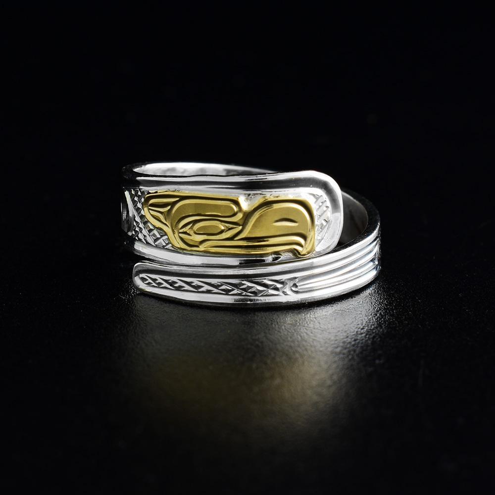 This wrap Thunderbird ring is made form sterling silver and 14K gold. The ring has a single, tapered band that wraps around the finger twice and has a depiction of the Thunderbird carved into it. The head of the Legend is made from gold.