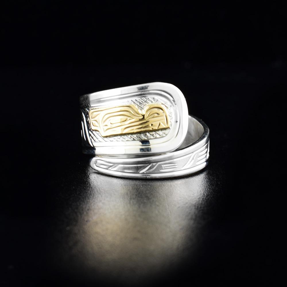 This Wolf ring is made from sterling silver and 14K gold and has a tapered band that wraps around the finger twice. There is a depiction of the Wolf that has been carved into the surface of the band. The face of the Wolf is made from 14K gold.