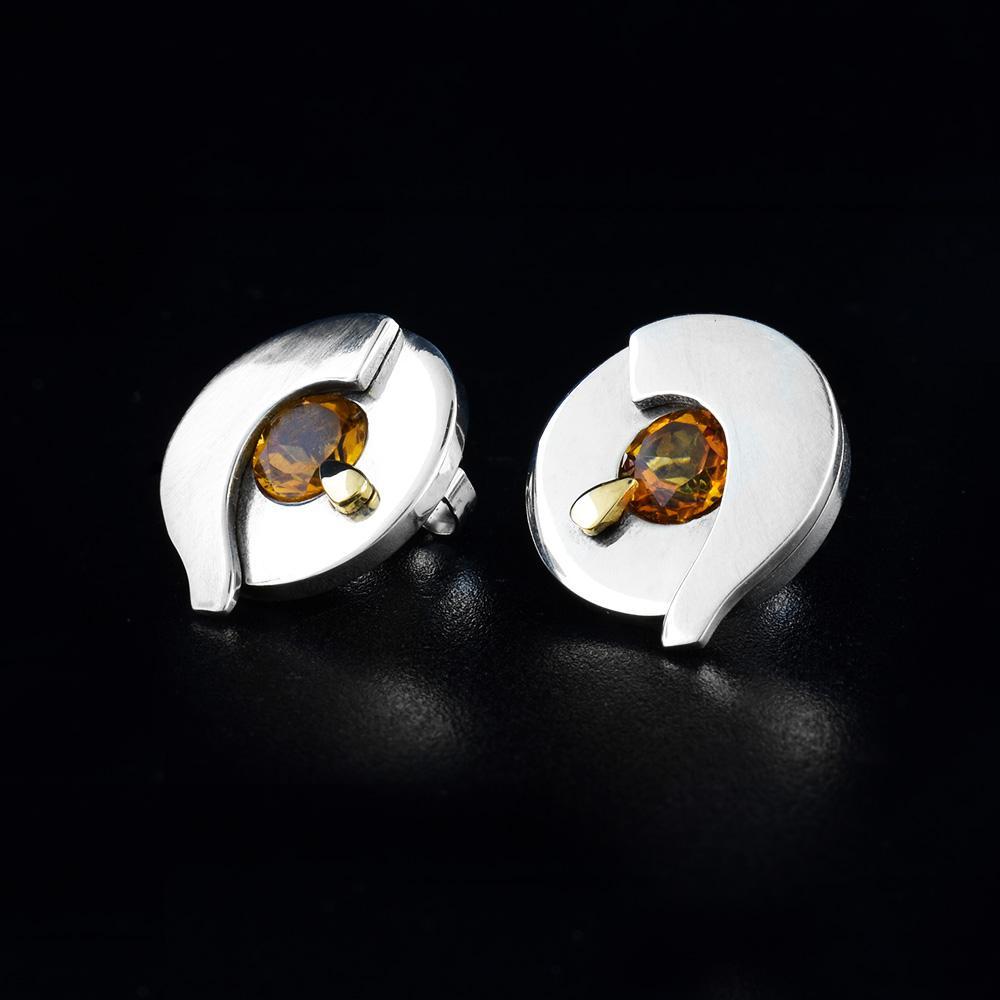 These citrine stud earrings are made with sterling silver, 14K gold and citrine gemstones. The earrings are circle shaped and have citrine gems imbedded in the center with gold embellishments below them.