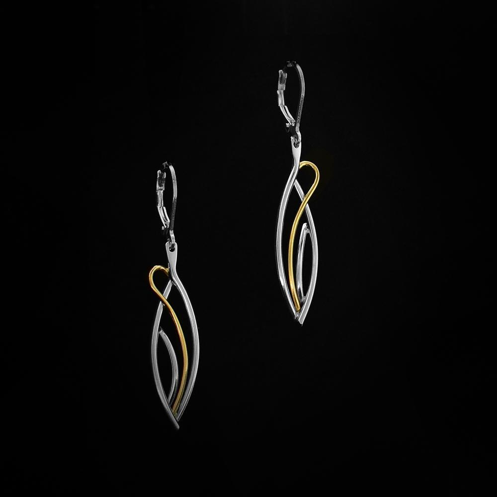 Long Flame Earrings by Lynda Constantine. Each Earring is in an oval shape. The artist has created gold and silver accents to add to each earring. The gold accent loops around the earring, replicating the flames of a fire.