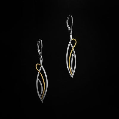 Long Flame Earrings by Lynda Constantine. Each Earring is in an oval shape. The artist has created gold and silver accents to add to each earring. The gold accent loops around the earring, replicating the flames of a fire.