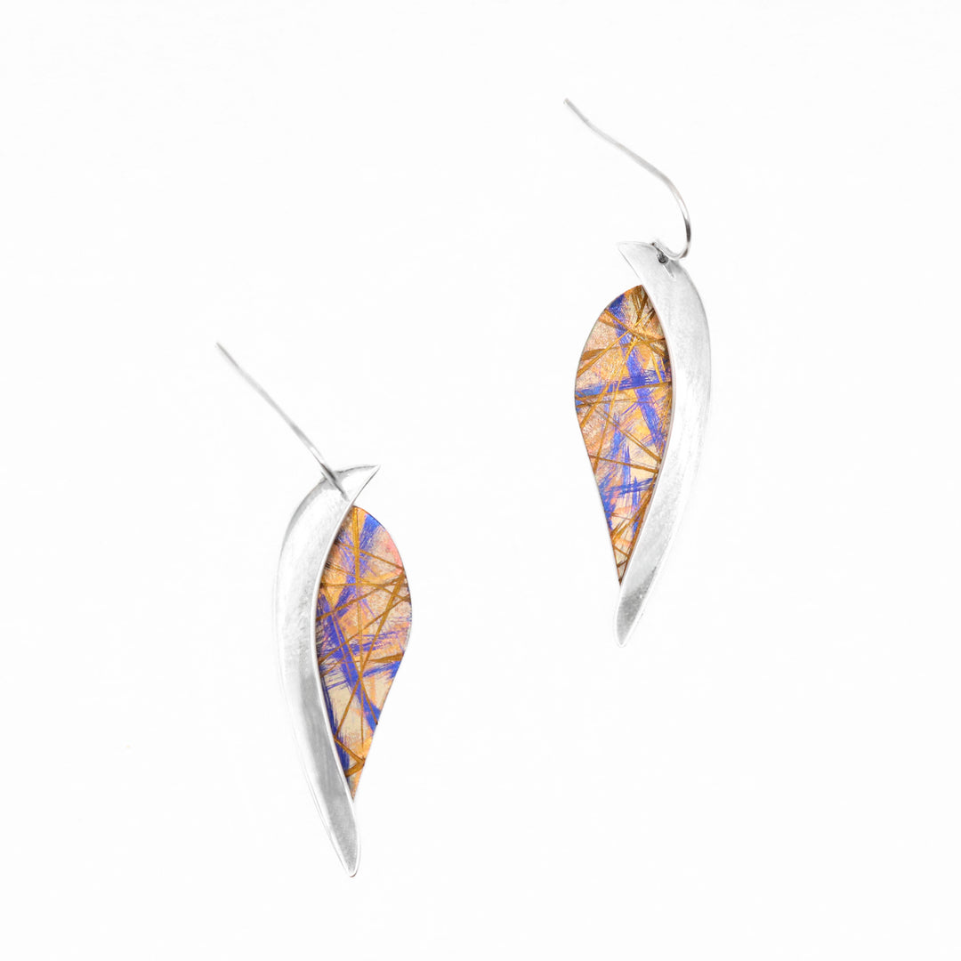 These titanium dangle earrings are made from sterling silver and anodized titanium. The hangs have a leaf shaped, titanium portion with a silver band running along the side of the piece. The titanium has a brilliant golden color and blue-ish designs on the surface of it that is achieved by anodizing the metal.