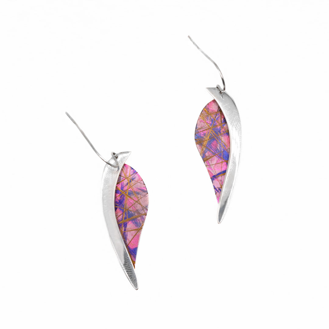 These titanium dangle earrings are made from sterling silver and anodized titanium. The hangs have a leaf shaped, titanium portion with a silver band running along the side of the piece. The titanium has a brilliant pink color and blue/gold designs on the surface of it that is achieved by anodizing the metal.