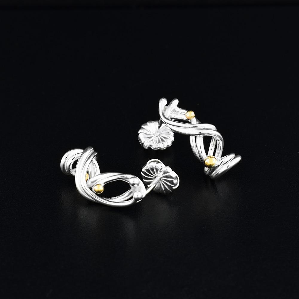 These drop, coil earrings are made from sterling silver and 14K gold. These earrings are made of coiled, silver wires that are curved around each other and there are gold beads featured along the wires.