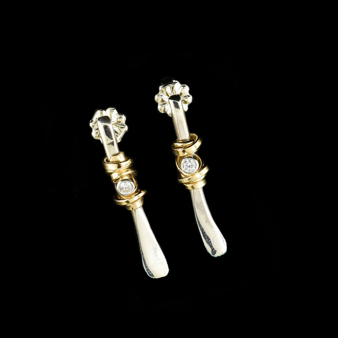 These cubic zirconia drop earrings have long, twig shaped drops made from sterling silver. There are cubic zirconia gems held at the top of the drops and there are 14K gold filled wires wrapped around the middle of the piece.