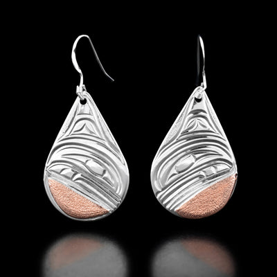 These teardrop earrings have the profile of an orca's head with a large fin above in each earring. There are copper accents at the bottom.