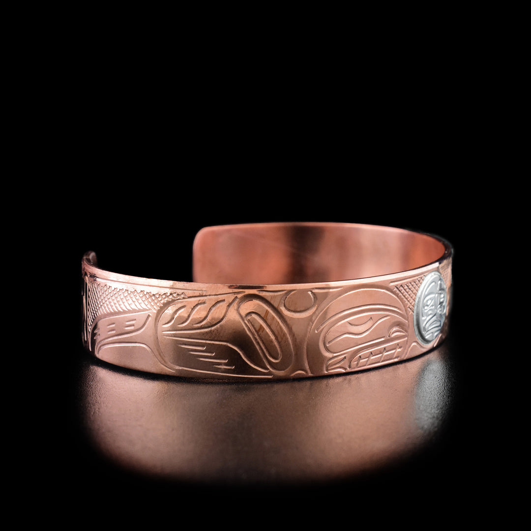 Left angle photo of this copper bracelet shows carved designs representing the orca's body and fins.