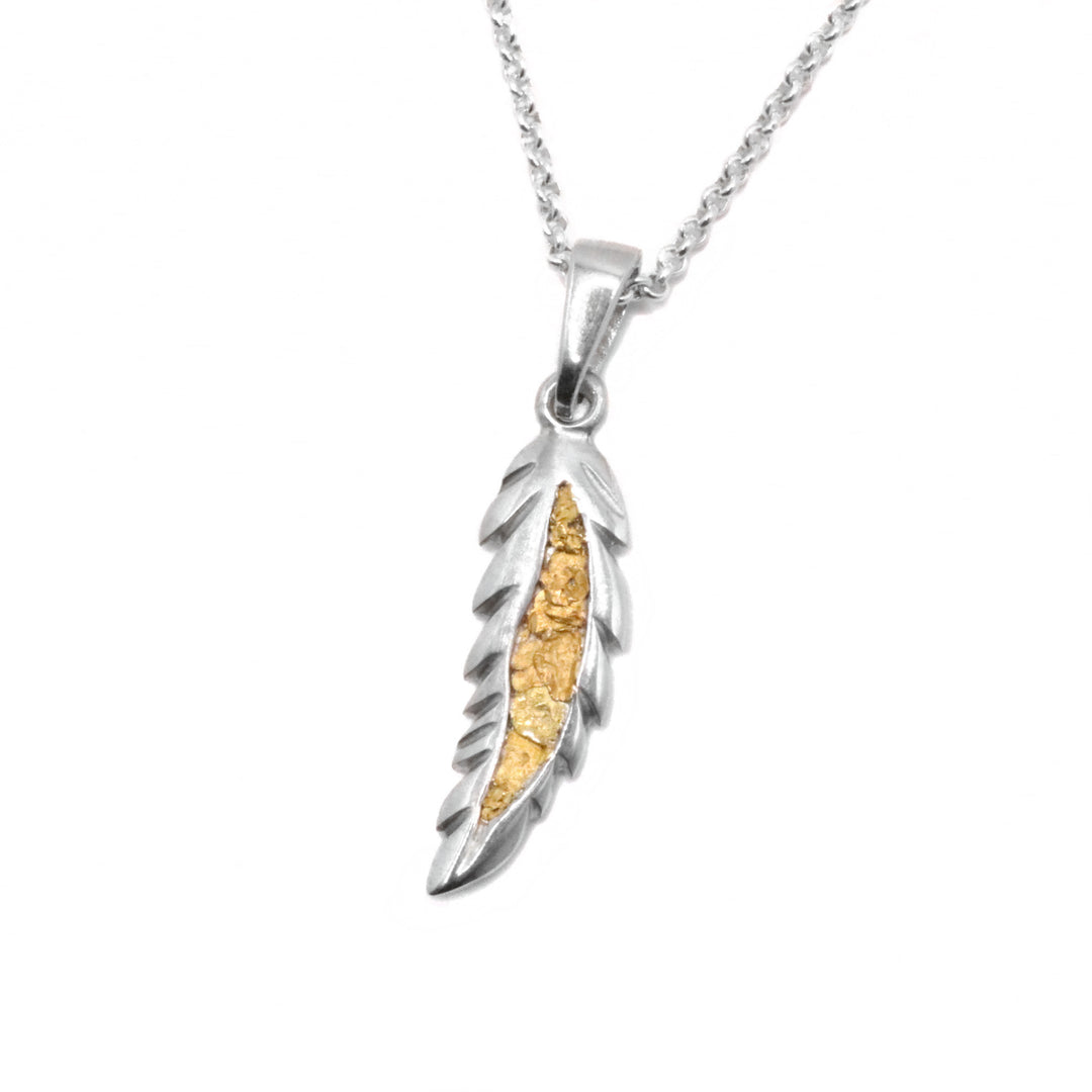 22K Gold Nugget Feather Pendant by Tom Gregorczyk. The pendant is in the shape of a feather. The artist has been 22k gold nuggets in the center of the feather with the rest of the piece being made out of sterling silver.