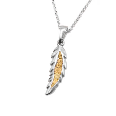 22K Gold Nugget Feather Pendant by Tom Gregorczyk. The pendant is in the shape of a feather. The artist has been 22k gold nuggets in the center of the feather with the rest of the piece being made out of sterling silver.