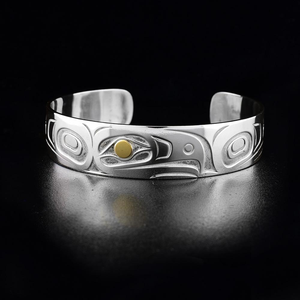 This Eagle bracelet is made from sterling silver and 18K gold and has a single band with a gap in the back. There is a depiction of the Eagle carved into the surface of the band.