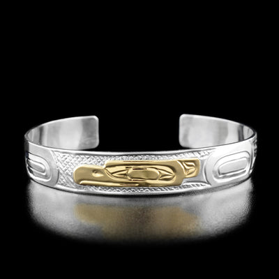 Sterling Silver and 14K Gold 3/8" Eagle Bracelet by Carrie Matilpi. In the center of the bracelet the artist has hand-carved the profile of an eagle's head looking towards the left out of 14k gold. To the right of the eagle's head the artist has hand-carved the eagle's body and wings. To the left of the eagle's head the artist has included intricate designs. The "background" of the bracelet has a hand-carved crisscross pattern that allows for the eagle legend to stand out.