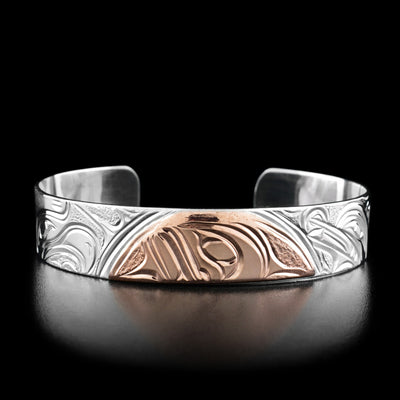 This cuff bracelet has half of the moons face in the center made out of copper.