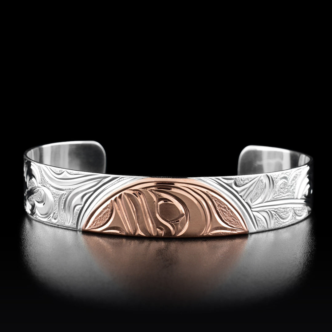 This cuff bracelet has half of the moons face in the center made out of copper.