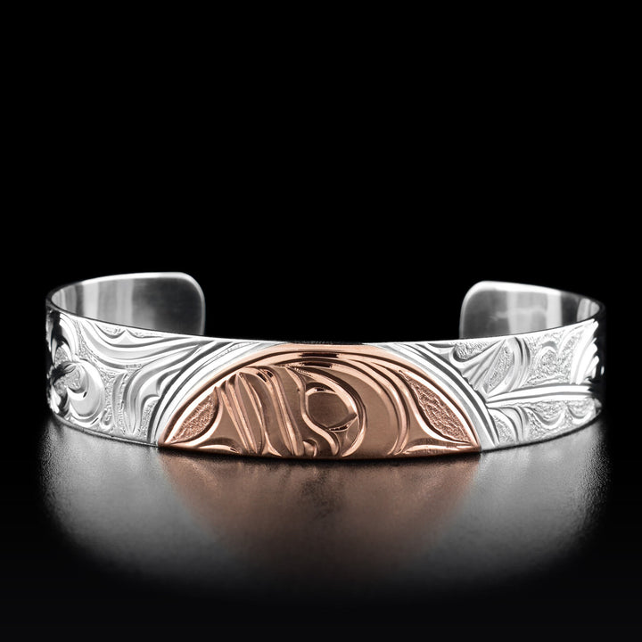 This cuff bracelet has half of the moons face in the center made out of copper.