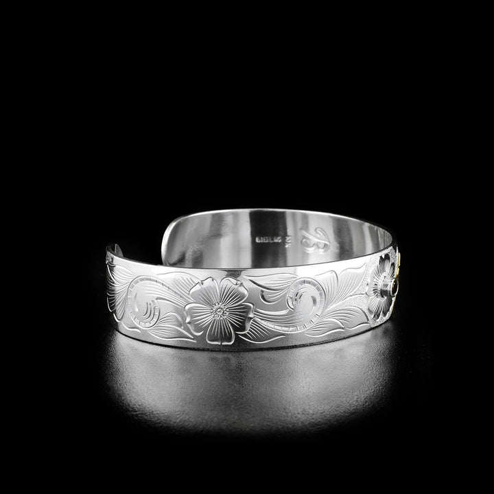 Left angle photo of the bracelet shows carved designs representing the stems and leaves of the flower the hummingbird is drinking from.