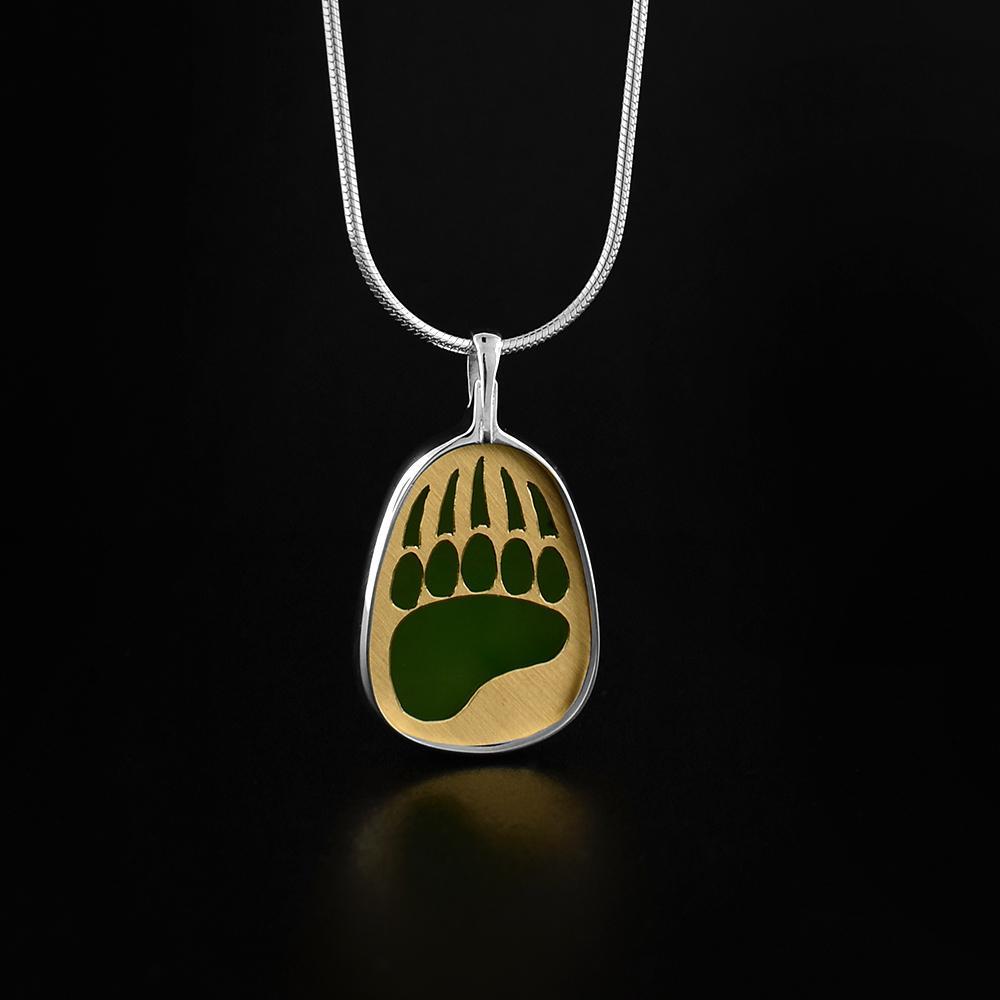 This gorgeous bear paw pendant is made from 14K gold, sterling silver and A+ grade BC jade. There is a bear paw cut out of a gold plate then set of the jade to give it a brilliant color. The pendant is oval shaped and is held in sterling silver.