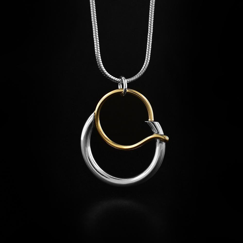 This gold and silver pendant necklace is made from 14K gold and sterling silver. The bottom half of the pendant is a silver hoop and has gold wire that goes over top of the silver hoop and through it.